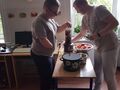 dwóch uczniów stoi przy sokowirówce i nakłada jabłka do sokowirówki