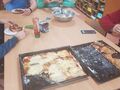 uczniowie siedzą przy stole i zajadają się pizzą