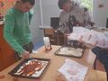 uczniowie stoją przy stole i nakładają składniki na ciasto od pizzy