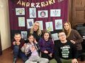 1 uczniowie i nauczycielki siedzą w siadzie skrzyżnym na podłodze w tle napis Andrzejki