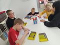 uczniowie siedzą przy stole w bibliotece i wykonują zadanie