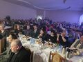 zdjęcie publiczności która siedzi na krzesłach przy stołach