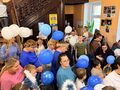 uczniowie i nauczyciele z białymi i niebieskimi balonikami stają w holu ośrodka