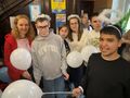 uczniowie z nauczycielami pozują do zdjęcia w holu ośrodka trzymają białe balony na głowach mają aureole