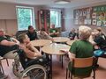 Uczniowie i goście siedzą przy stolikach i rozmawiają