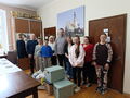 zdjęcie grupowe Pani Dyrektor goscie i uczniowie stoją w pomieszczeniu przed nimi stoją paczki