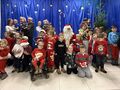 2 dzieci rodzice nauczyciele stoją na scenie razem z mikołajem w środku pozują do zdjęcia grupowego