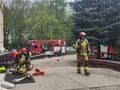 Strażacy przygotowują niezbędny sprzęt przed głównymi schodami Ośrodka. W tle wozy strażackie 
