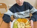 chłopiec pokazuje talerz na którym sa pokrojone owoce
