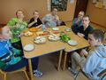 dzieci siedza przy stole na którym są warzywa na kanapki pokrojone