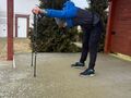 Nauczyciel pokazuje ćwiczenia rozciągające z wykorzystaniem kijków do nordic walking. 