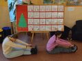 Dwie dziewczynki siedzą na ziemi i wykonują skłon do stóp