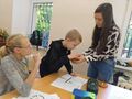 uczniowie siedzą przy ławce w klasie i losują dla siebie cytat