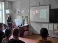 uczniowie siedzą przy ławkach w klasie i oglądają film edukacyjny