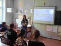 uczniowie siedzą przy ławkach w klasie i słuchają prelekcji