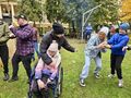 6. Uczniowie i nauczyciele stoją w kole podają sobie ziemniaka z rąk do rąk w tle ognisko 