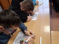 uczniowie siedzą przy ławkach w klasie i kolorują mandale
