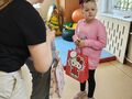 Dziewczynka trzyma w ręce prezent. Kolega składa życzenia urodzinowe. Wszyscy znajdują się w klasie 