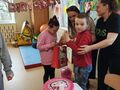 Uczennica kl. I świętuje swoje 9 urodziny wraz z kolegami i paniami. Chłopiec oraz osoby dorosłe składają życzenia urodzinowe 