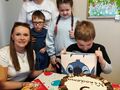 Zdjęcie przedstawia 3 uczniów oraz 2 panie. Chłopiec świętuje swoje 9 urodziny. 