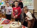 Na zdjęciu widoczni są uczniowie kl. I wraz z paniami. Jeden z chłopców ma urodziny. Koleżanka i kolega składają życzenia 