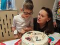 Zdjęcie przedstawia chłopca oraz panią. Przed uczniem stoi tort. Dziecko świętuje swoje 7 urodziny 