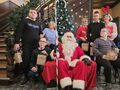 13 mikołaj siedzi na fotelu dzieci i nauczyciele z klasy obok mikołaja pozują do zdjęcia