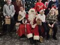 7 mikołaj siedzi na fotelu dzieci i nauczyciele z klasy obok mikołaja pozują do zdjęcia