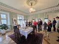 Uczniowie zwiedzają muzeum znajdują się w pomieszczeniu w którym na środku stoi zastawiony stół