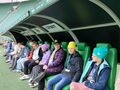 uczniowie na stadionie siedzą na ławce trenerskiej