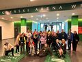 uczniowie pozują do zdjęcia na stadionie w hali wyjścia na murawę na zielonym tle napis Tarczyński Arena