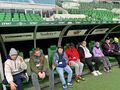 uczniowie siedzą na ławce trenerskiej na stadionie