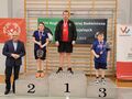 13 zawodnicy stoją na podium z tylu napis olimpiady specjalne oraz nazwa zawodów