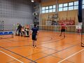 9 zawodnicy grają mecz badminotna obok siedzą oczekujący zawodnicy
