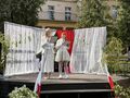 Nauczycielka z uczennicą odczytują wiersz na scenie za szkołą