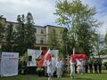 Uczniowie i nauczyciele tańczący z dwiema flagami przed sceną