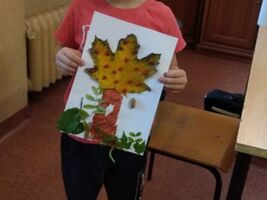 chłopiec trzyma pracę plastyczną wykonaną z liści