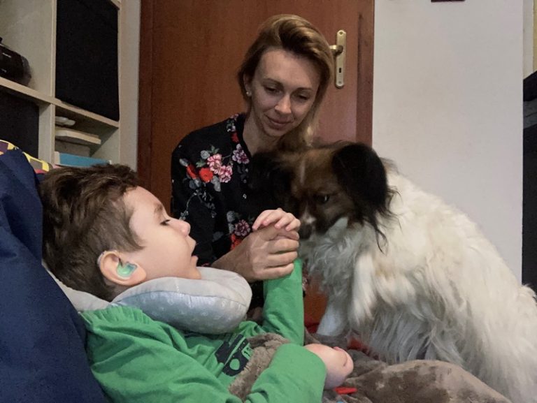 Pies dotyka nosem dłoni ucznia, dogoterapeutka trzyma rękę ucznia