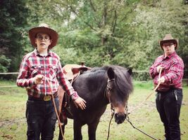 Szymon i Mateusz wcielili się w rolę kowboi pozując do zdjęć z Rokim, chłopcy trzymają konia za wodze, koń stoi pomiędzy nimi