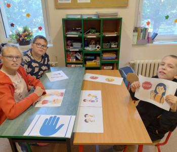 uczniowie siedzą przy ławkach w klasie i uczą się komunikatu STOP