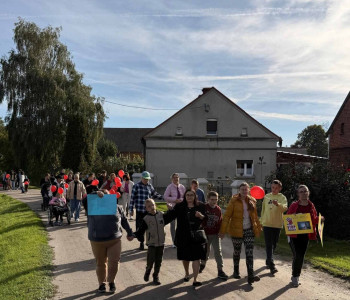 uczniowie uczestniczą w marszu przeciw przemocy wraz z plakatami i czerwonymi balonami
